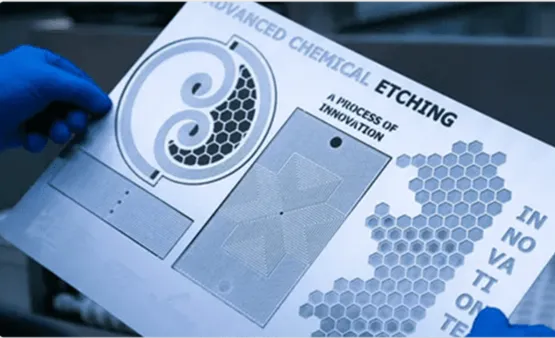 Hand holding a metal sheet with intricate raised chemical etching patterns.