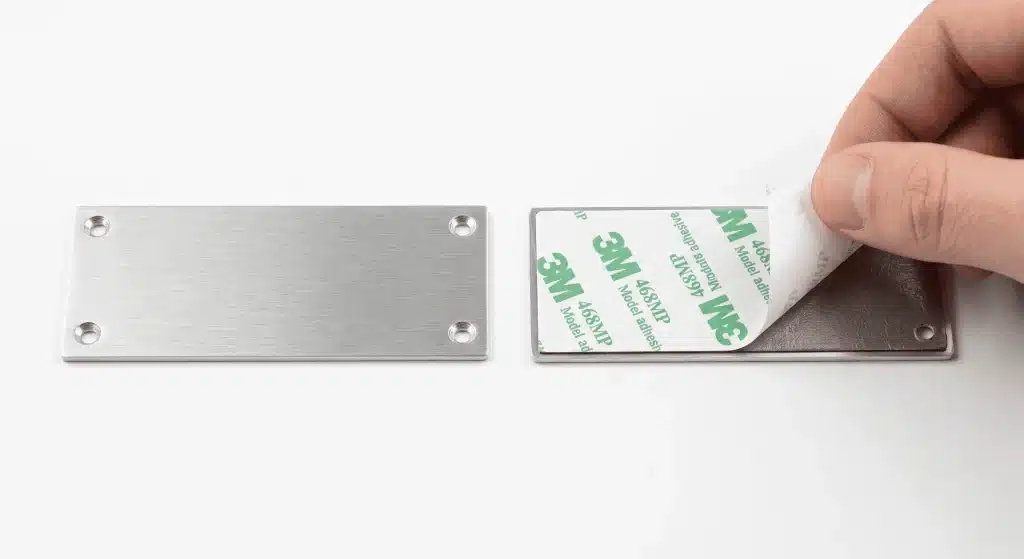 Porównanie tabliczki aluminiowej z otworami na śruby i tabliczki z podkładem samoprzylepnym 3M